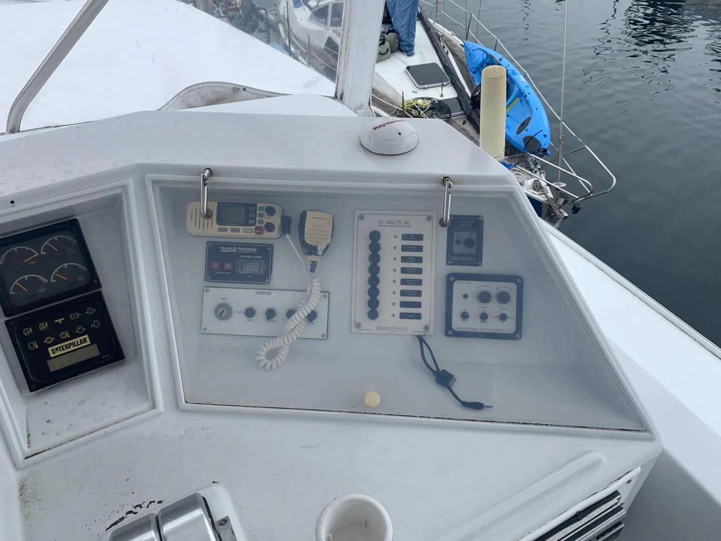 a white boat with a blue sail aboard REHAB Yacht for Sale