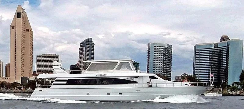 a white yacht in front of a city aboard REHAB Yacht for Sale
