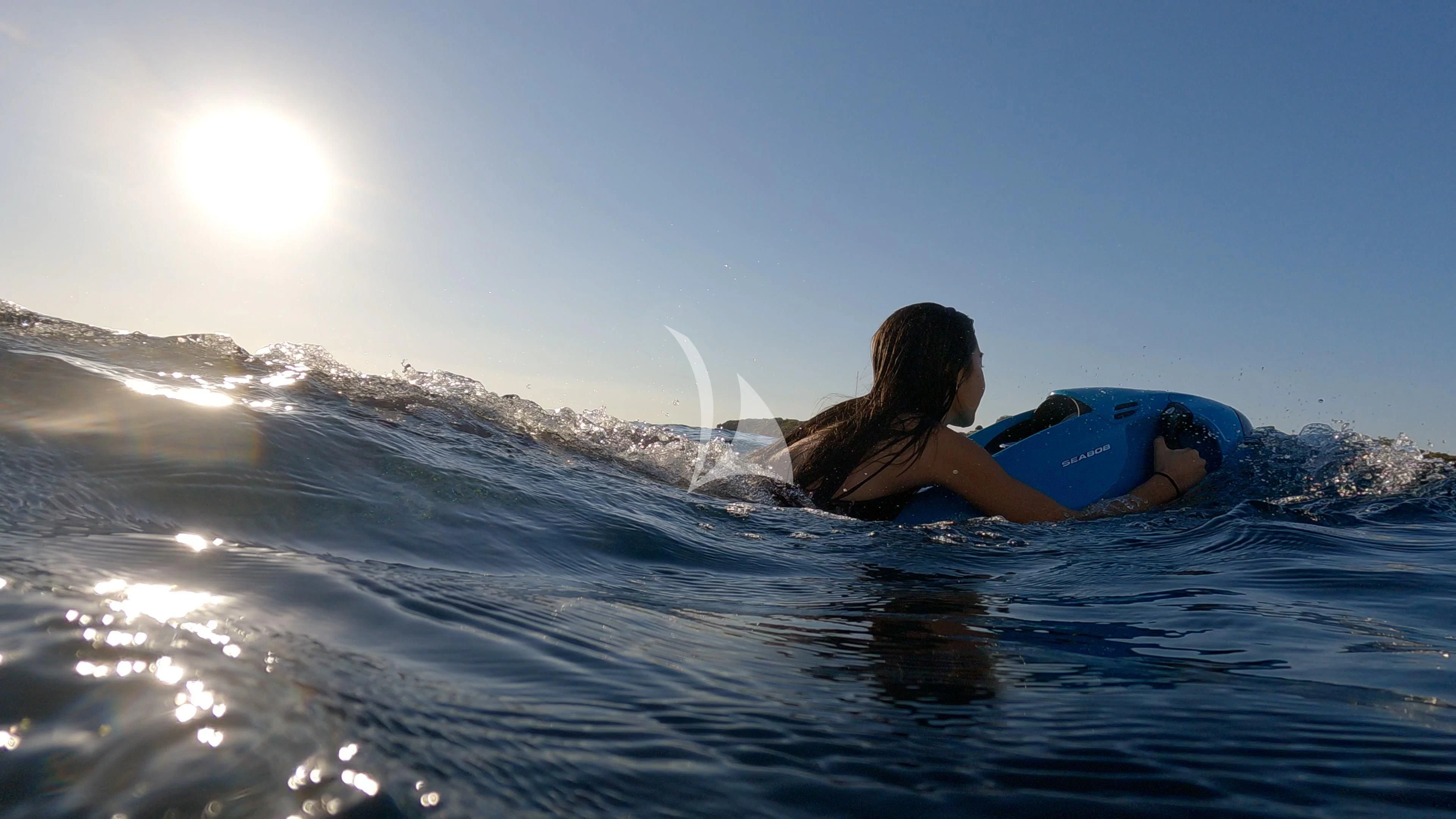 a man lying on a surfboard in the water aboard AKIRA ONE Yacht for Charter