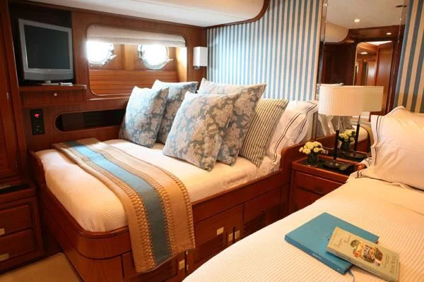 a bed with a pillow and a television on the wall aboard GITANA Yacht for Charter