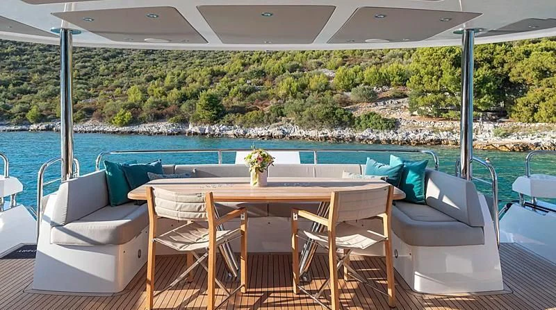 a table and chairs on a deck overlooking a body of water aboard HUNKY DORY OF LONDON Yacht for Sale