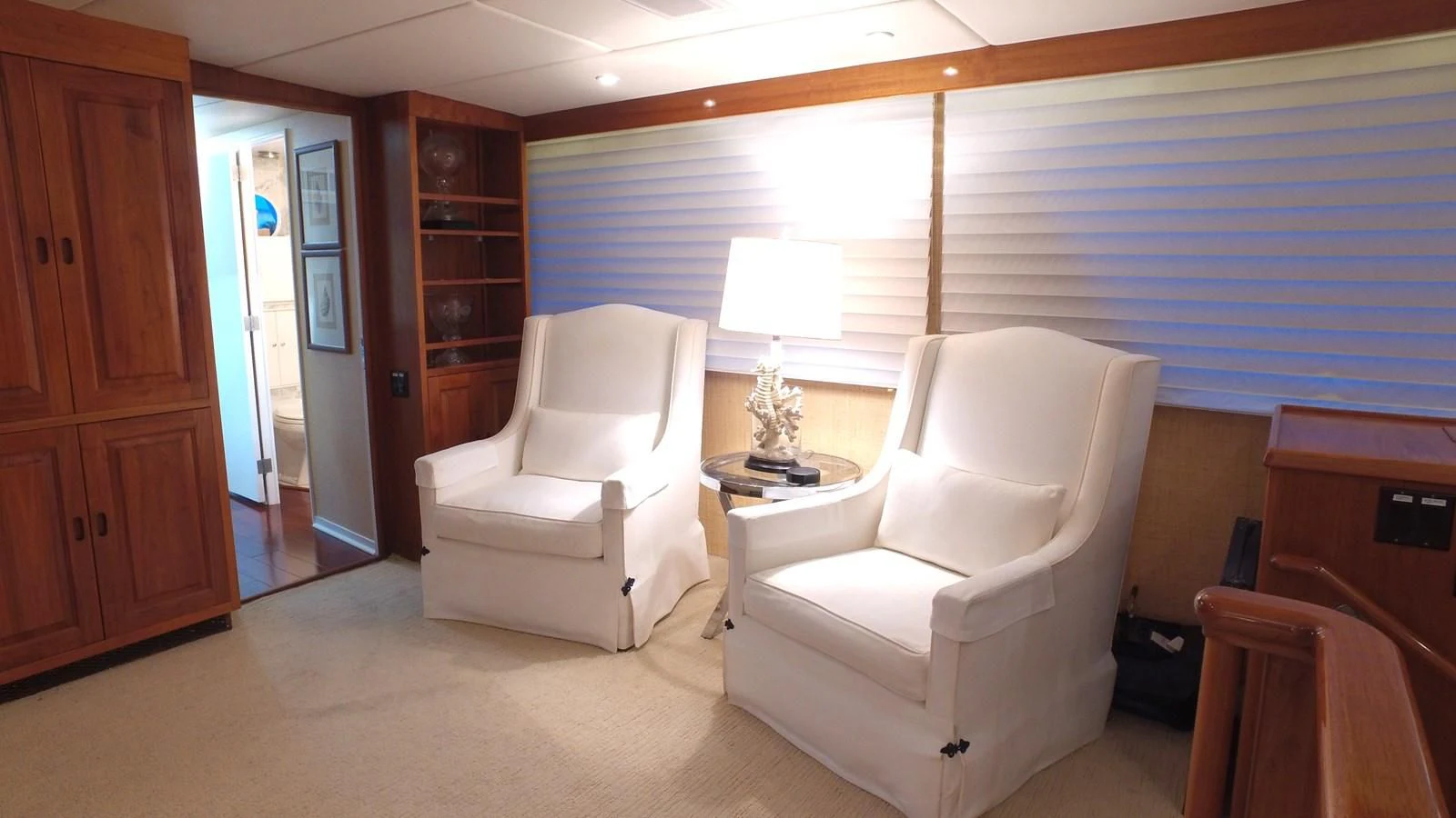 a room with a couple of white chairs and a table with a lamp aboard BAREFOOT V Yacht for Sale