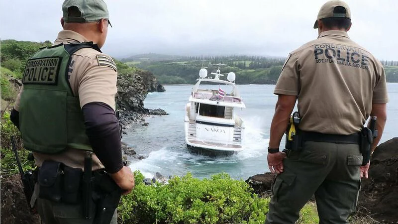 a couple of men looking at a boat in the water aboard NAKOA Yacht for Sale