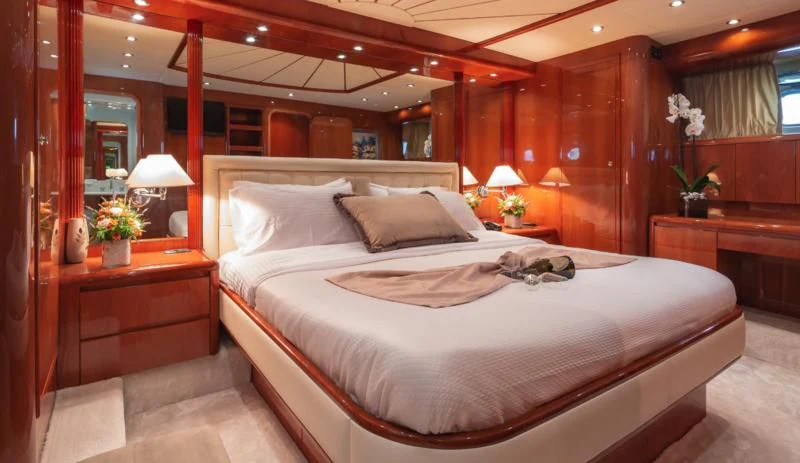 a bed with a white sheet and pillows in a room with wood walls aboard EFMARIA Yacht for Sale