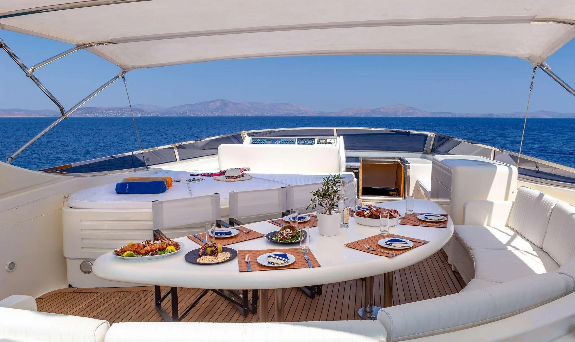 a large white lounge chair next to a large white table with food on it aboard EFMARIA Yacht for Sale