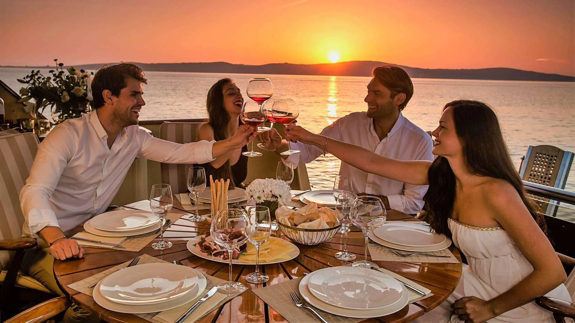 a group of people sitting around a table with wine glasses and food aboard AURIANE Yacht for Sale