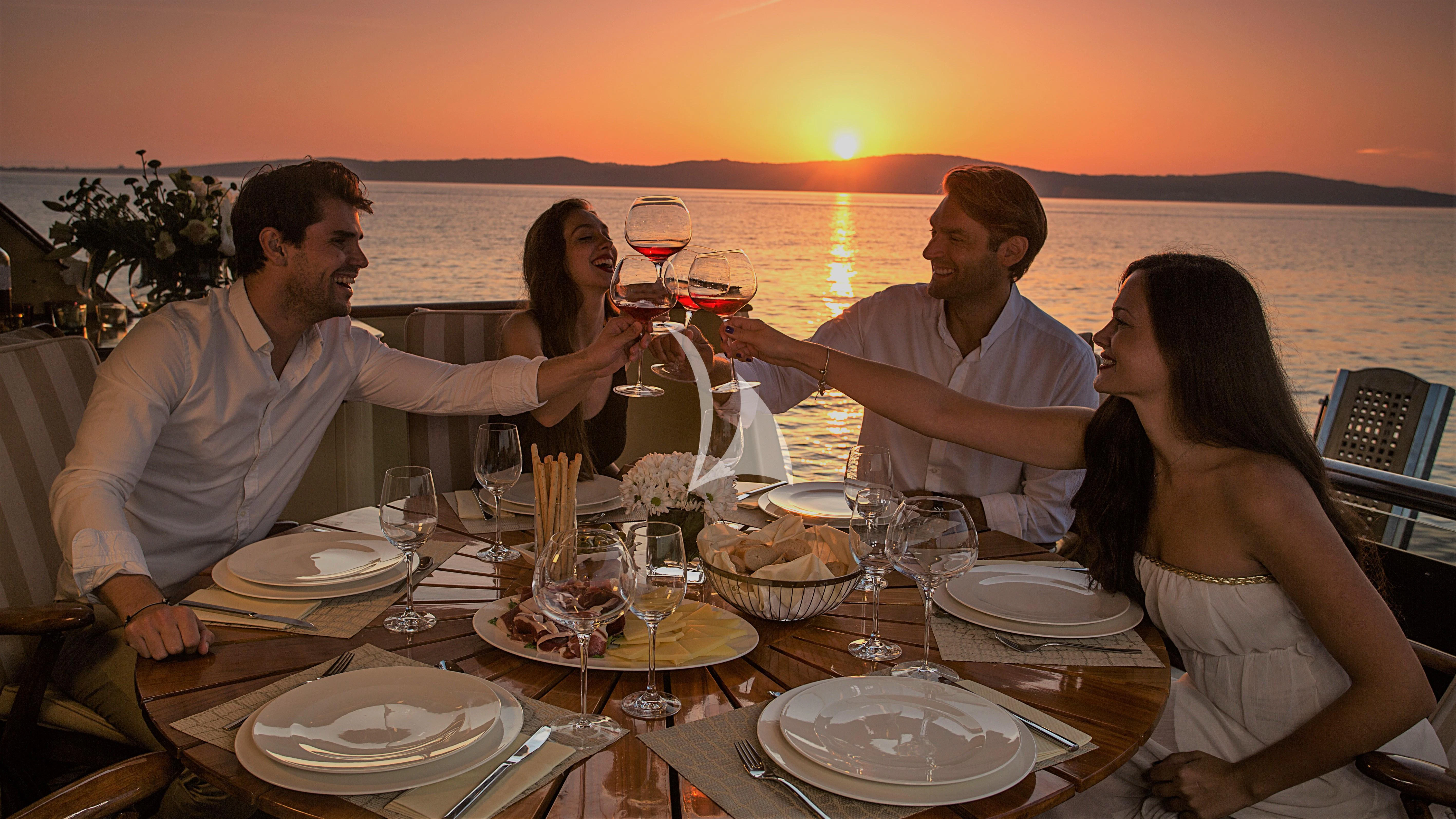 a group of people sitting around a table with wine glasses aboard AURIANE Yacht for Sale