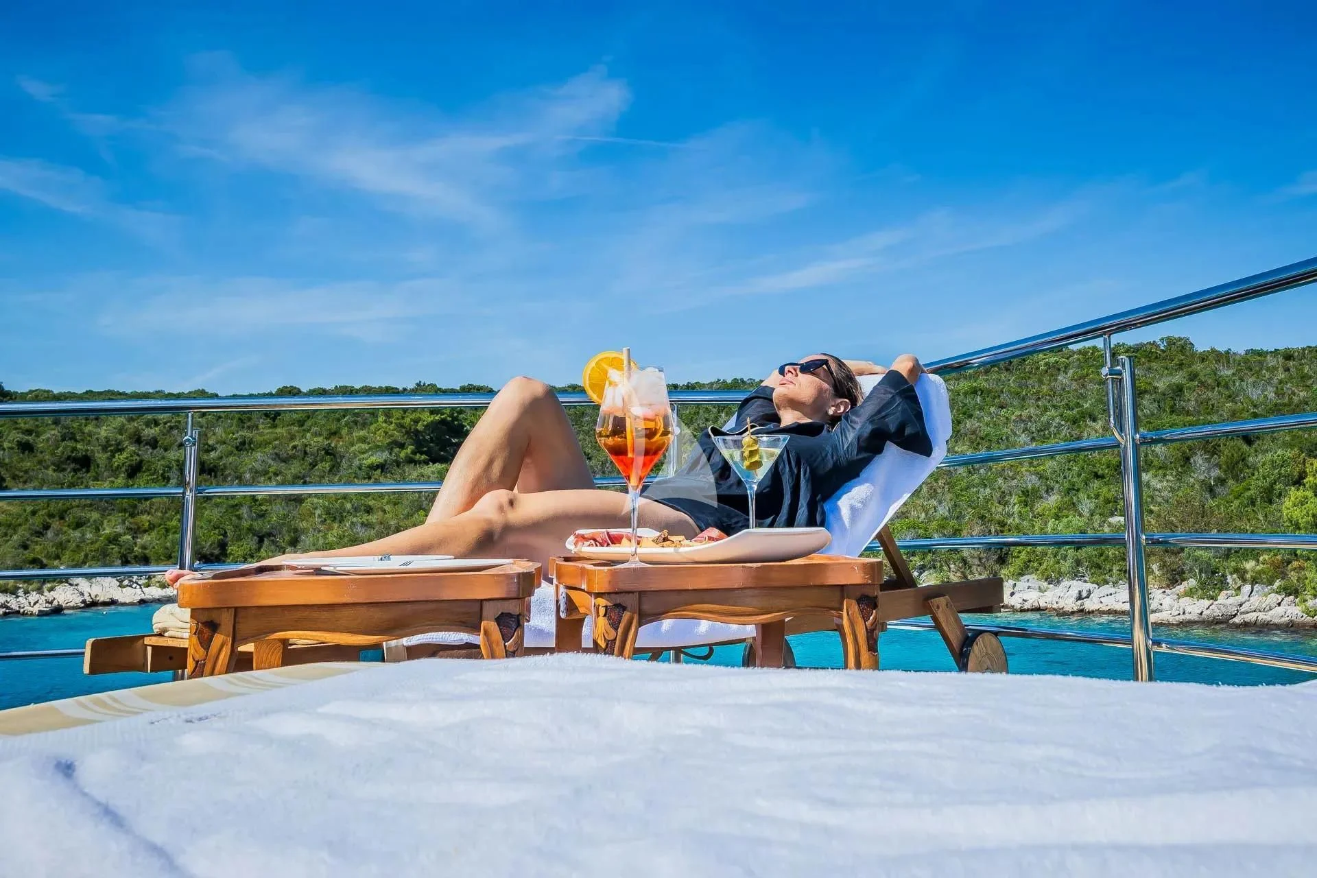a person lying on a bench with a glass of wine aboard AURIANE Yacht for Sale