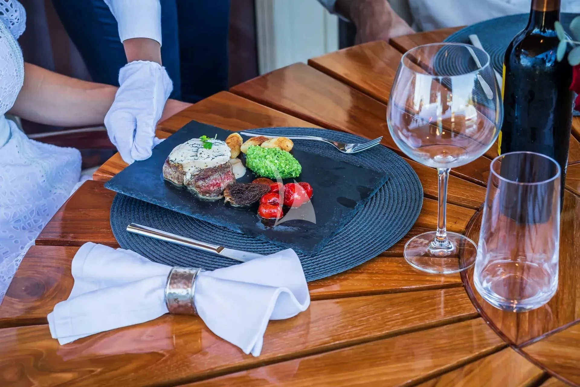 a plate of food and wine aboard AURIANE Yacht for Sale