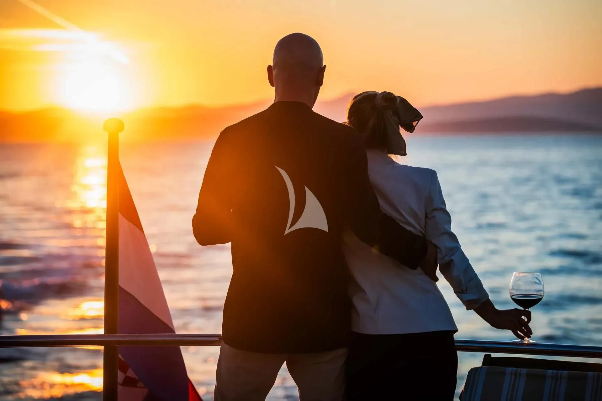 a couple of people holding a glass of wine looking at the sunset aboard AURIANE Yacht for Sale