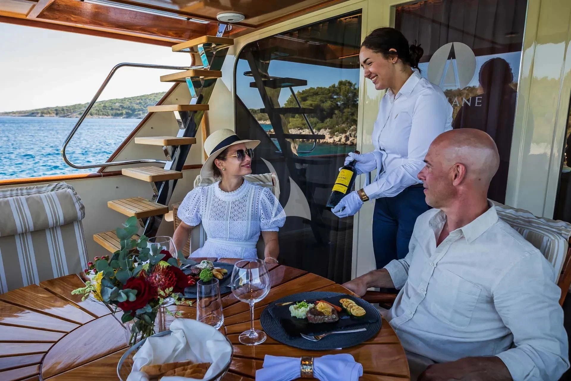 a group of people sitting at a table with food and drinks aboard AURIANE Yacht for Sale