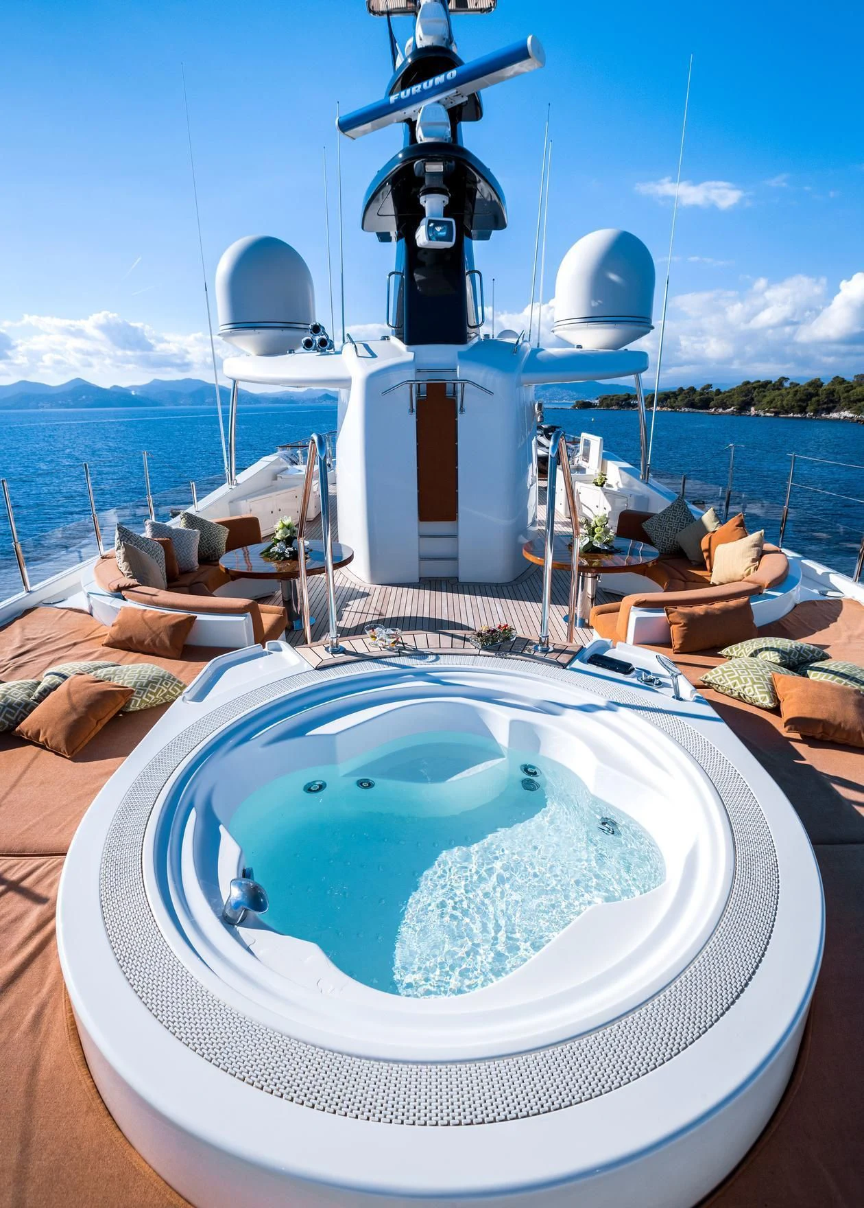 a large white swimming pool on a boat with a view of the ocean and mountains in the background aboard PHOTON Yacht for Sale