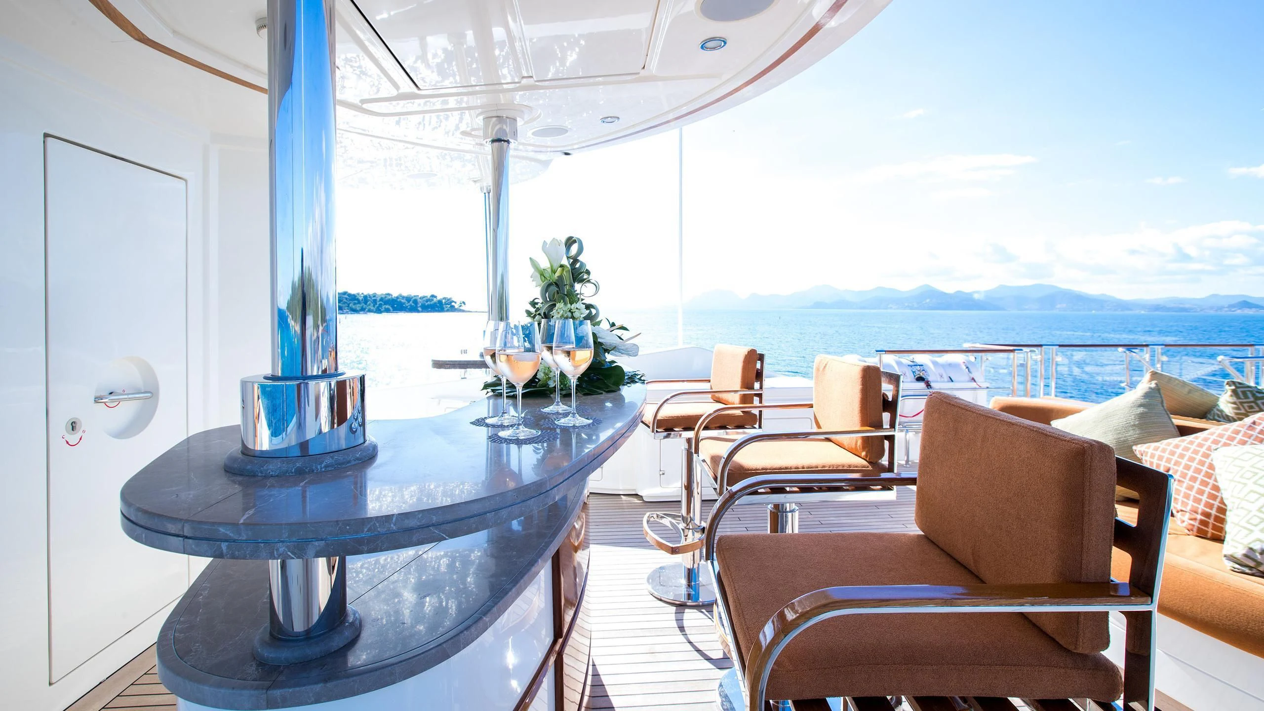 a table with chairs and a glass on a balcony aboard PHOTON Yacht for Sale