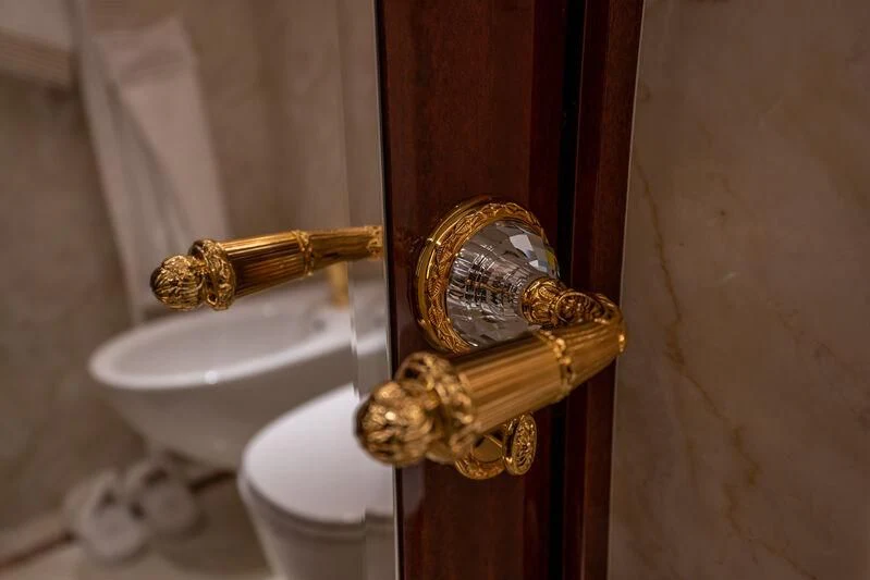 a gold door handle on a white toilet aboard JEWELS Yacht for Sale