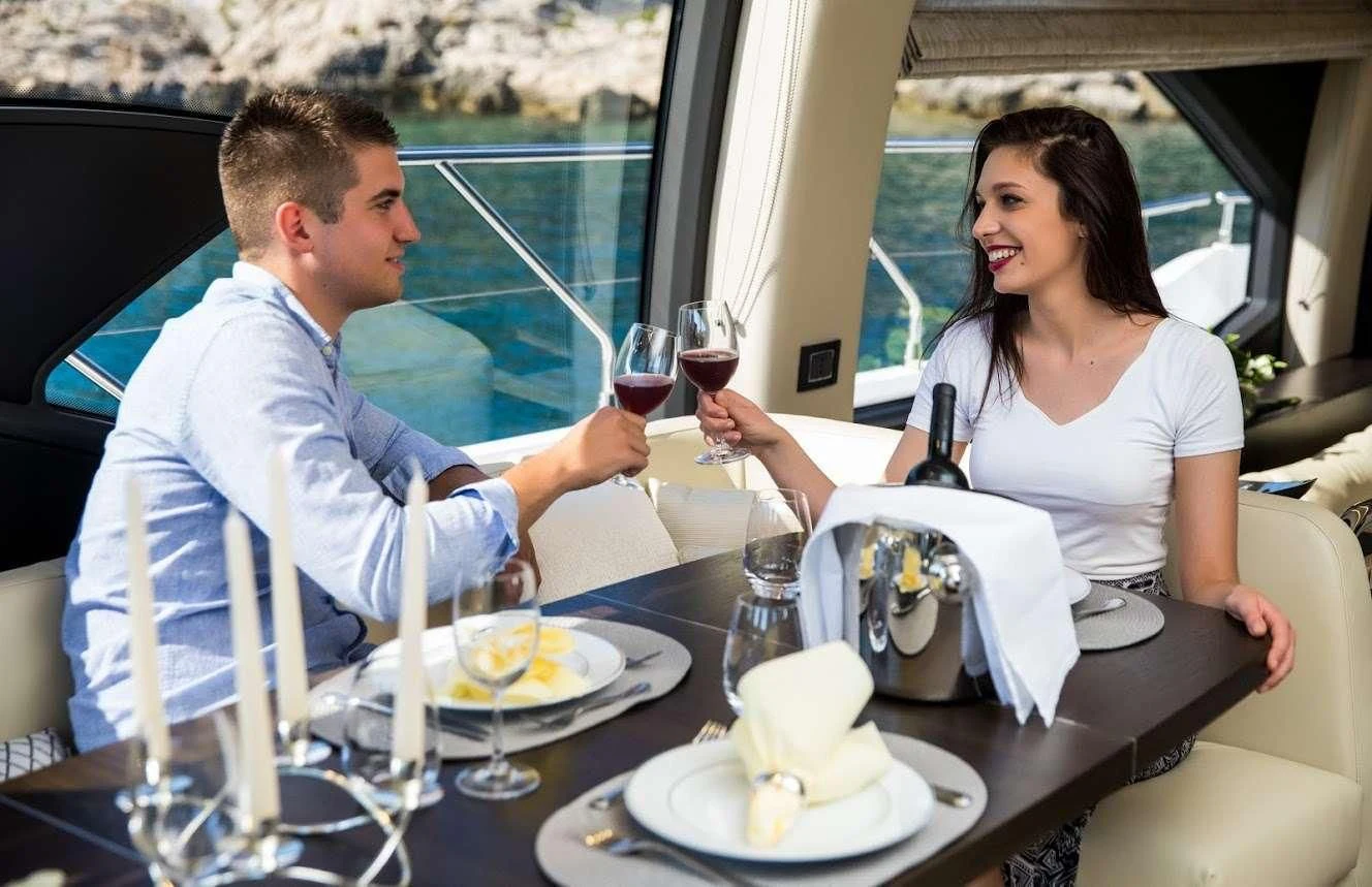 a man and woman sitting at a table with wine glasses and food aboard TAMARA II Yacht for Sale