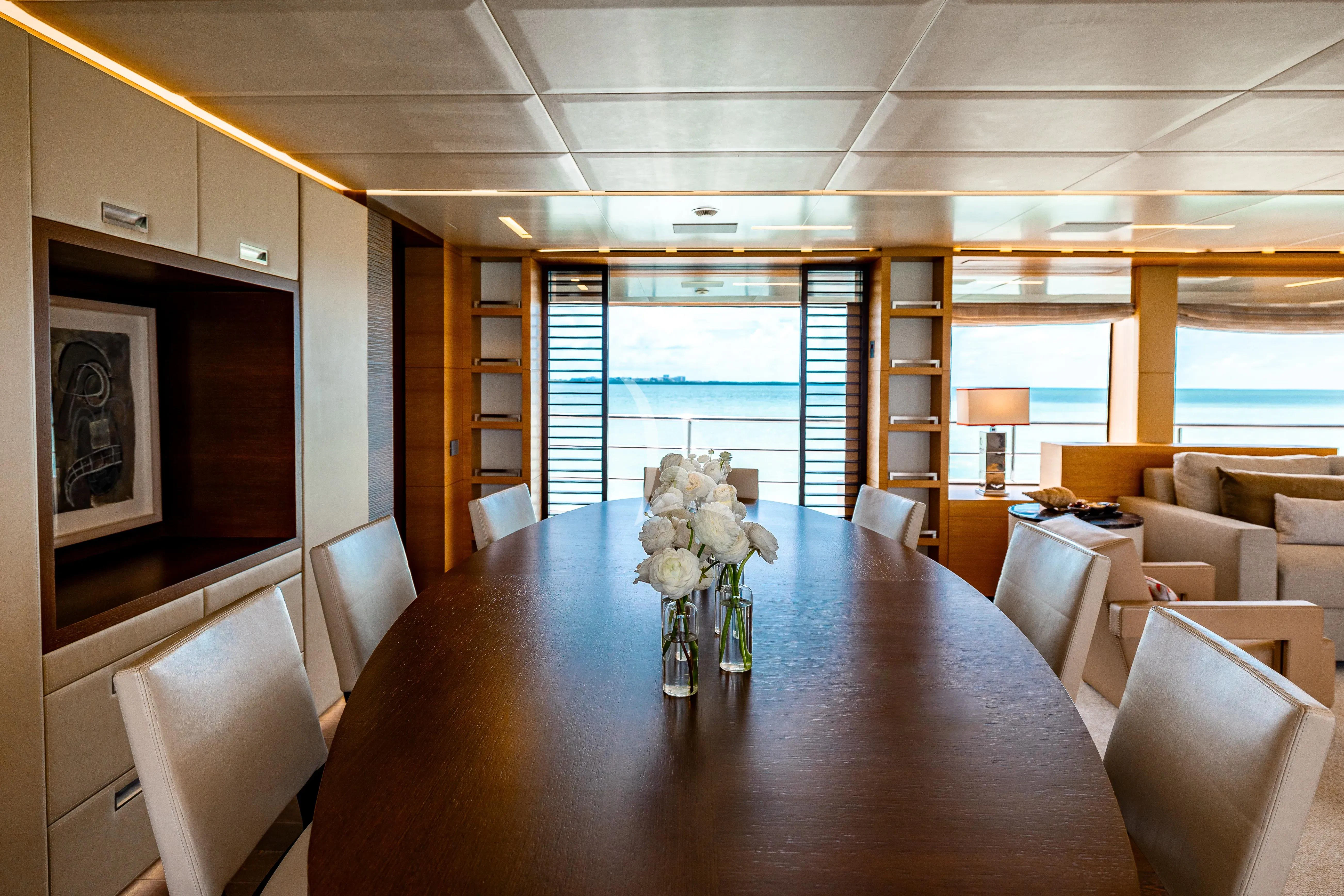 a large room with a table and chairs and a large window aboard PATIENCE Yacht for Charter
