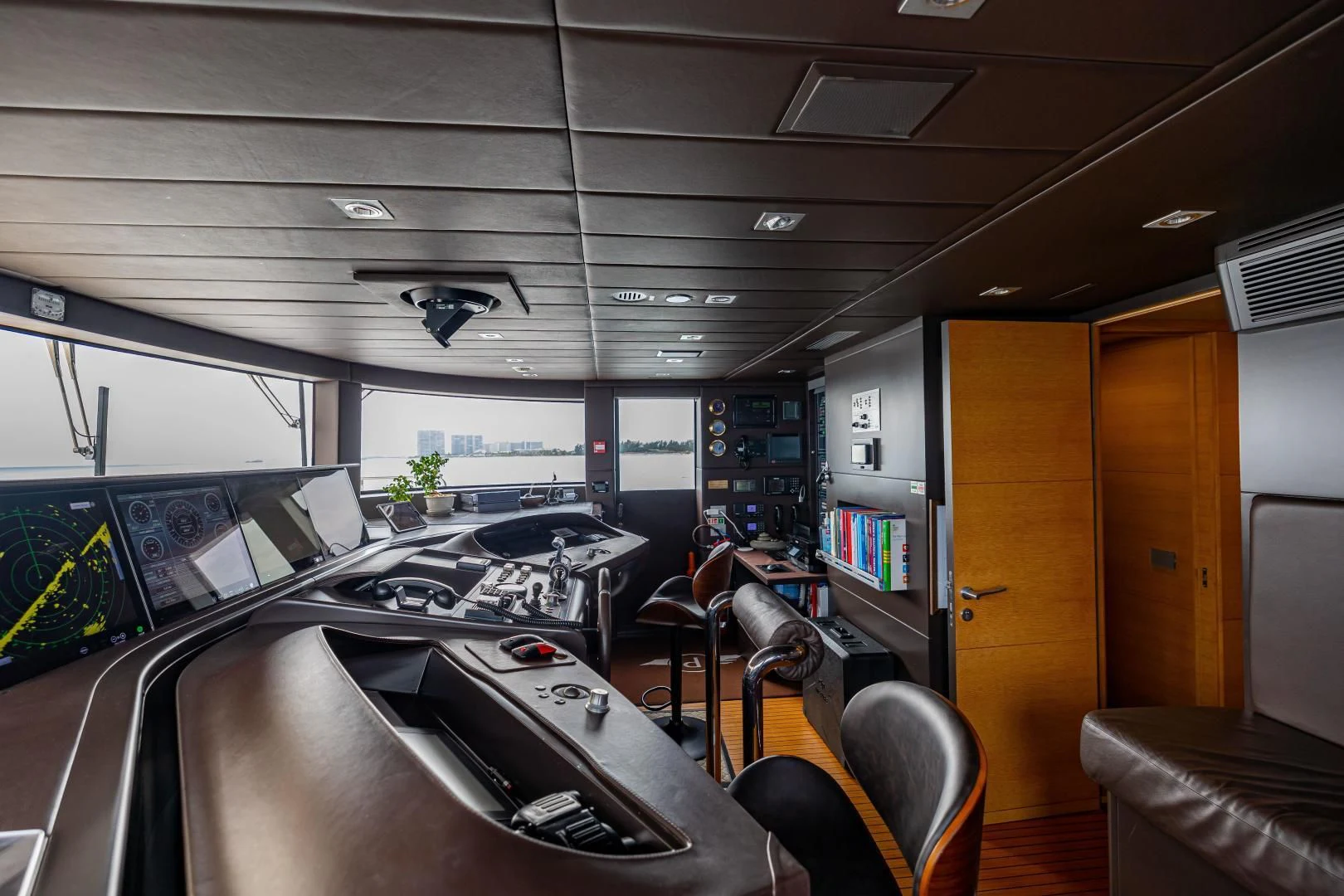 a room with a piano and a desk with chairs and a large window aboard PATIENCE Yacht for Charter
