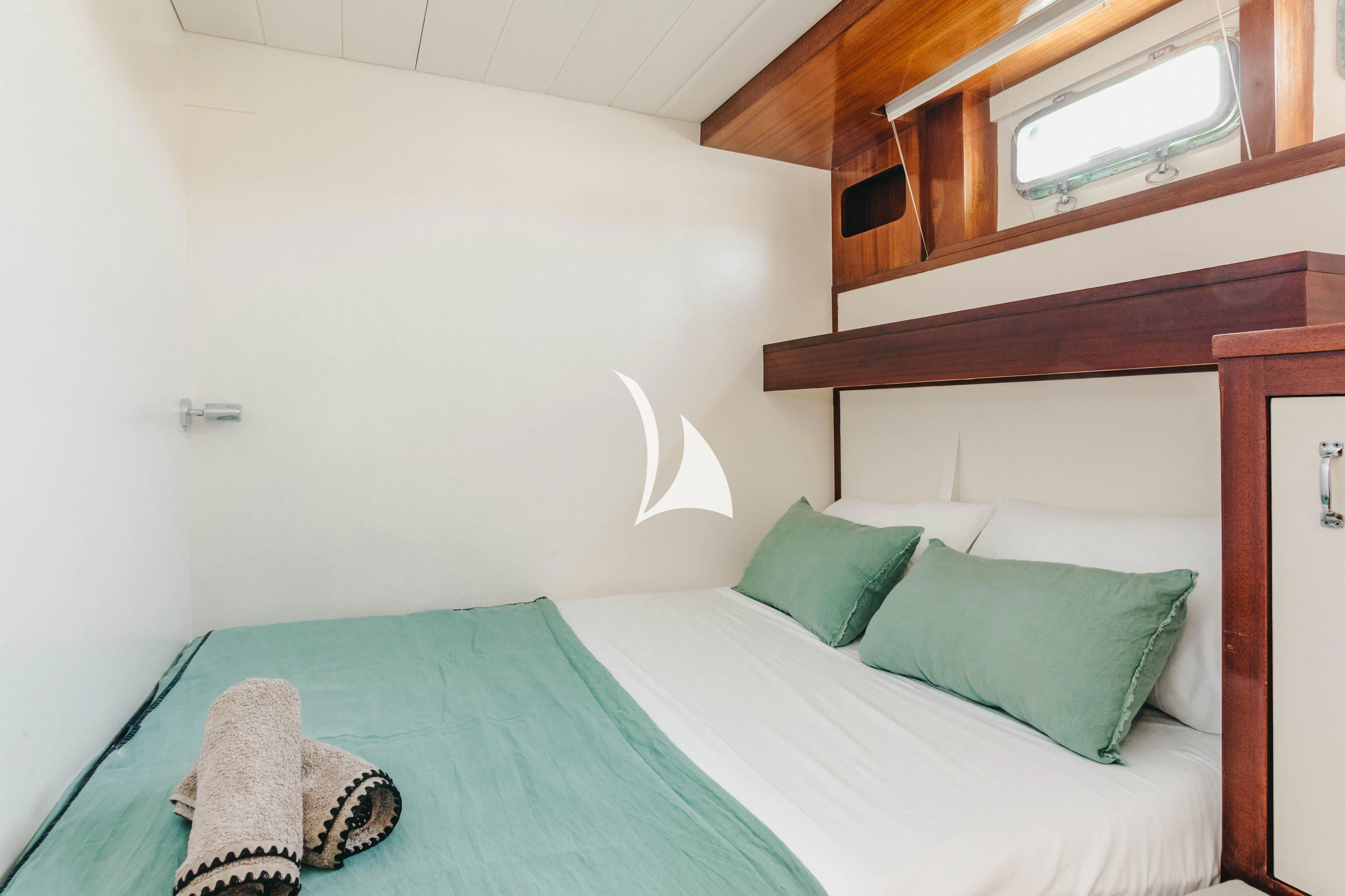 a bed with a green blanket aboard CIUTADELLA Yacht for Sale