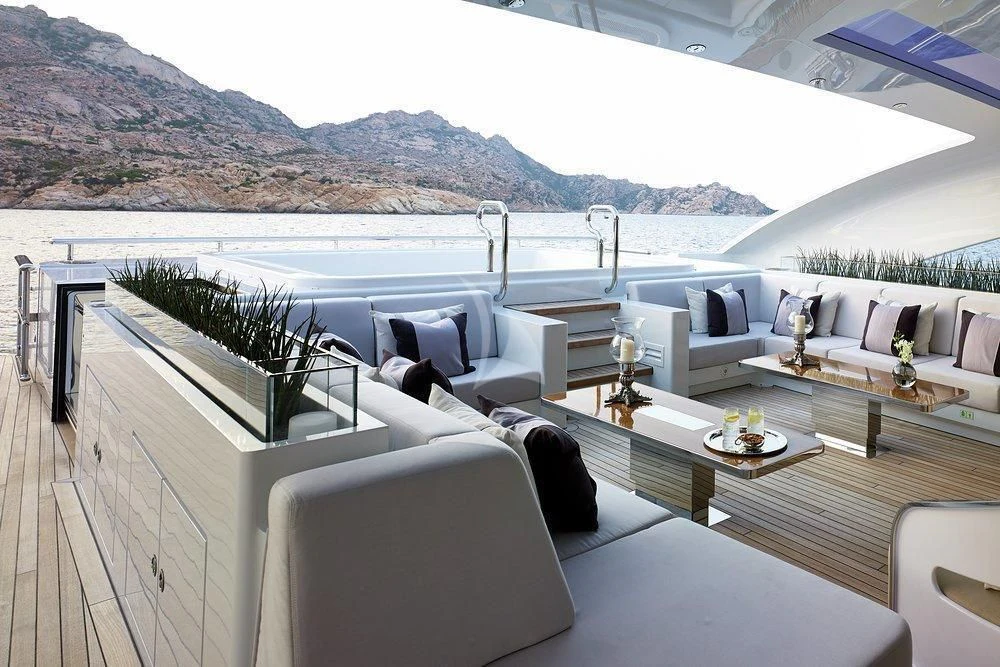 a living room with a large body of water and mountains in the background aboard ILLUSION Yacht for Sale