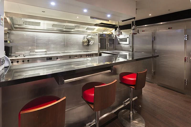 a kitchen with a large stainless steel counter and stools aboard ILLUSION Yacht for Sale