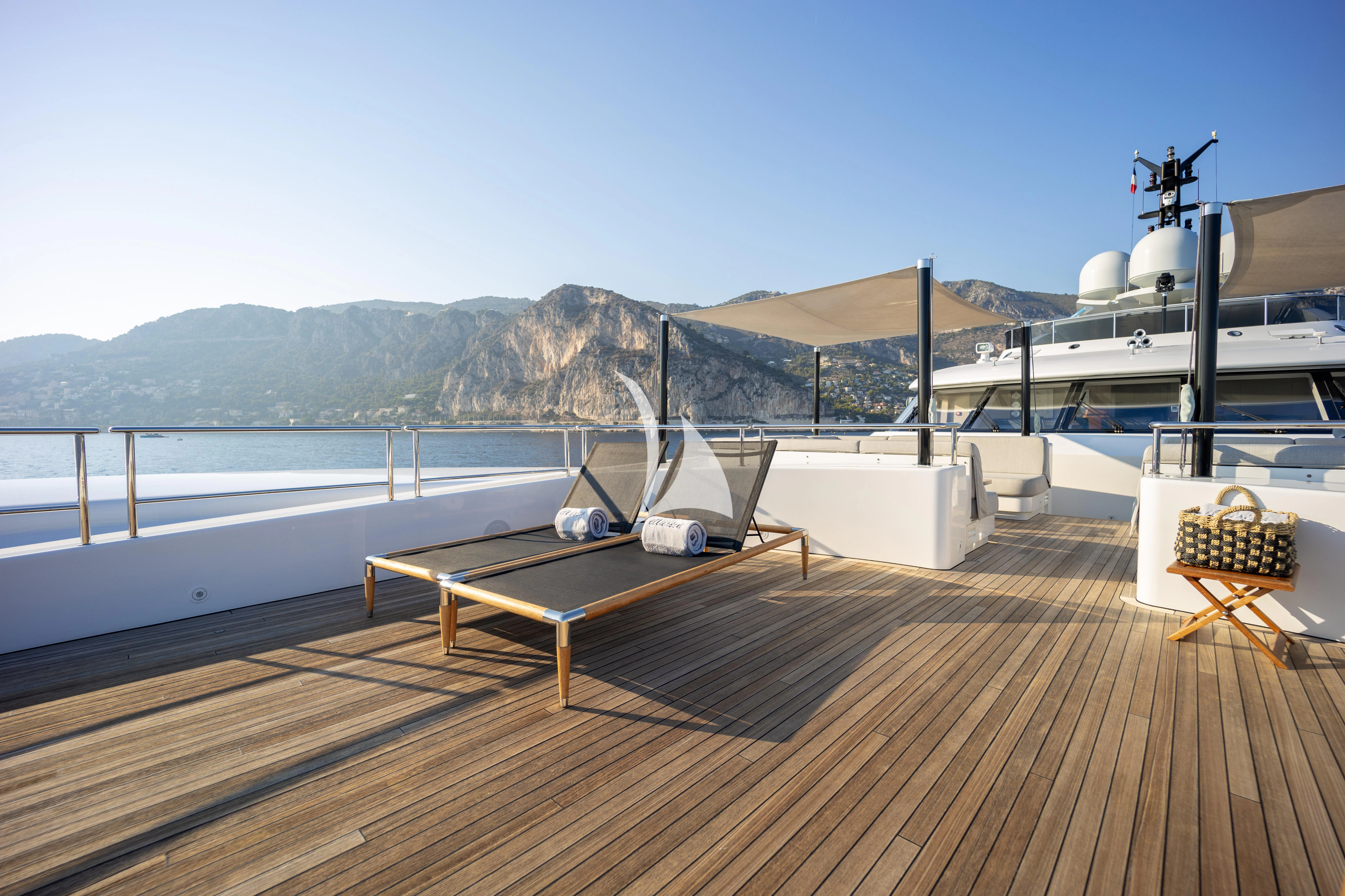 a deck with a boat and a body of water in the background aboard ILLUSION Yacht for Sale