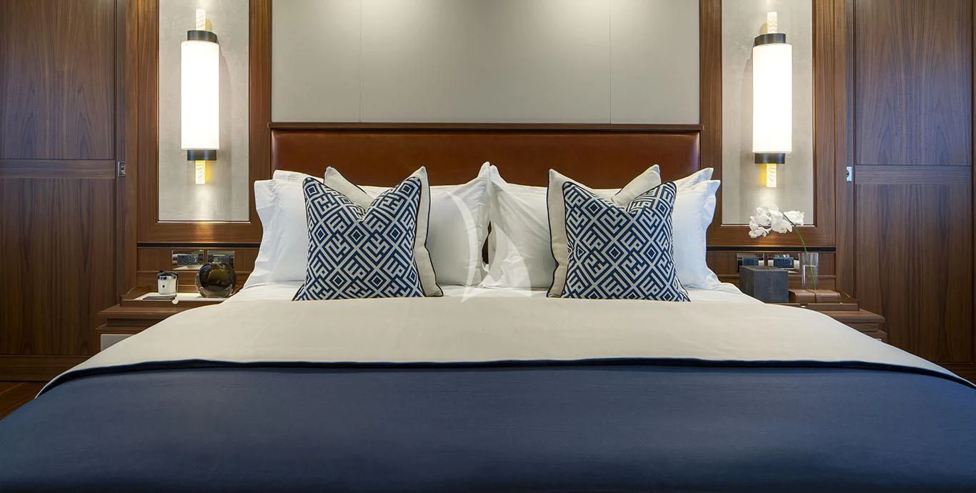a bed with a blue sheet and pillows aboard RANIA Yacht for Sale