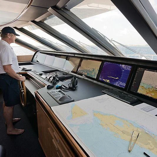 a man standing next to a table with computers on it aboard BARENTS Yacht for Charter