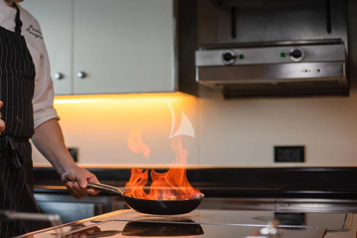 a person cooking food in a pan aboard BARENTS Yacht for Charter