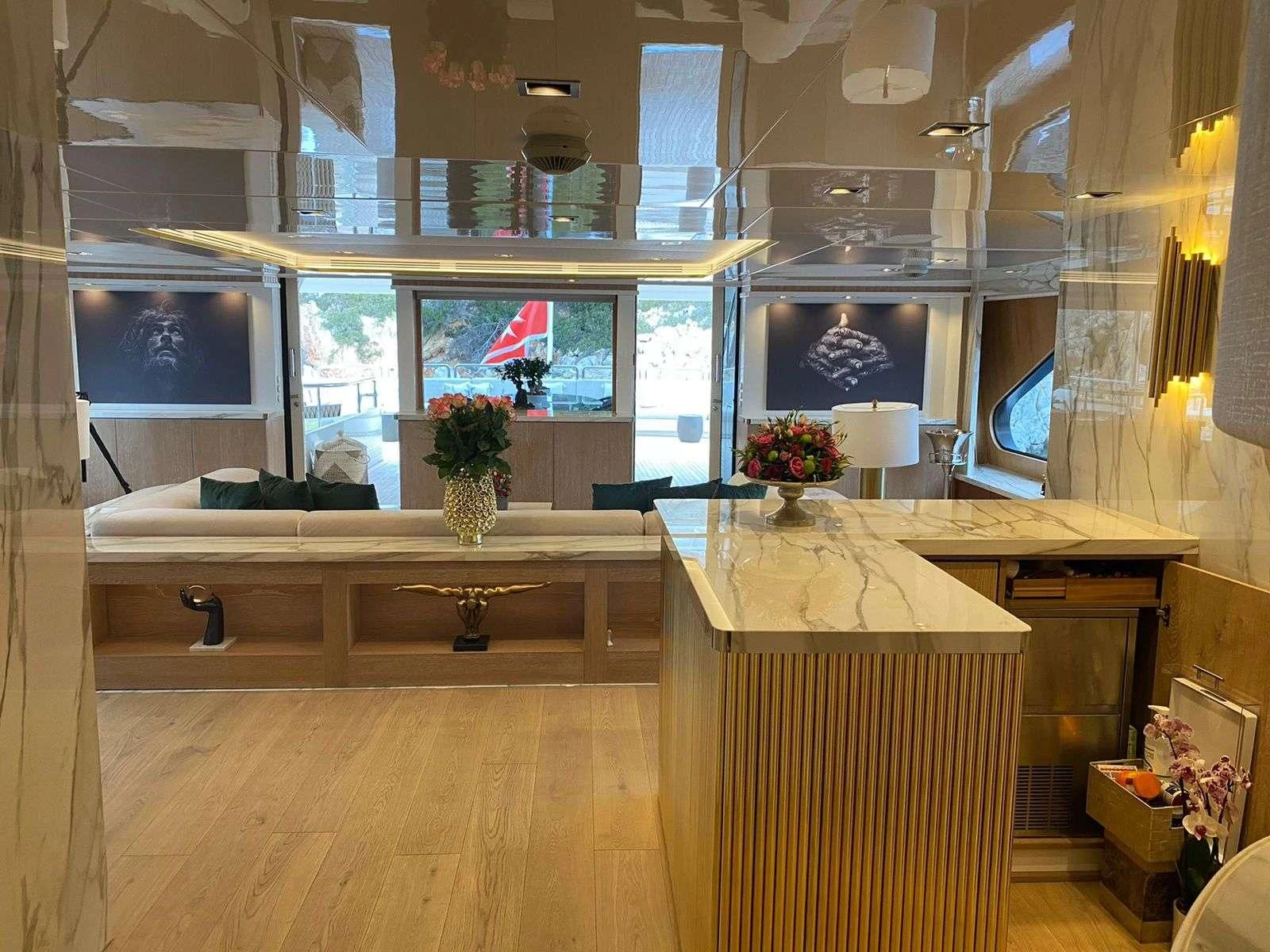 a room with a large window and a desk with a vase of flowers aboard BARENTS Yacht for Charter