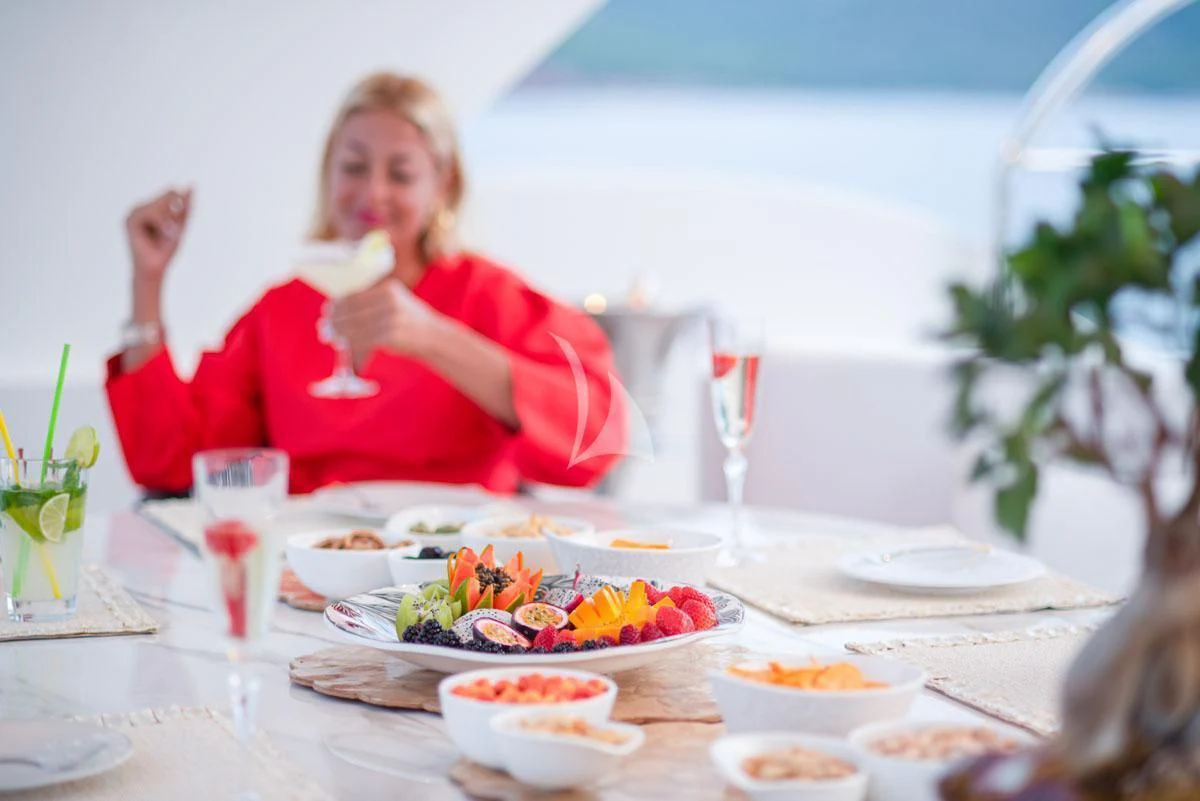 a woman sitting at a table with food on it aboard BARENTS Yacht for Charter