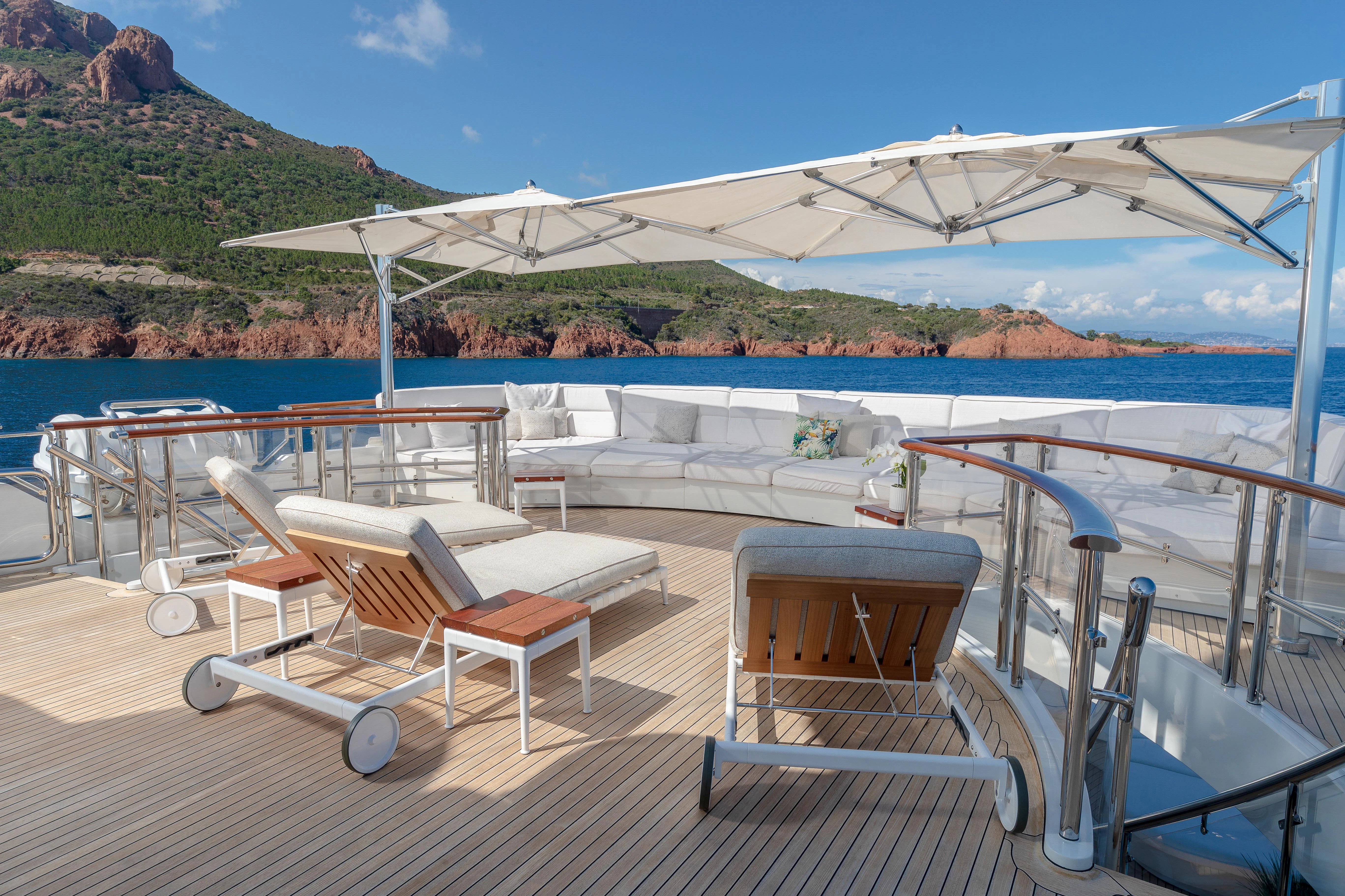 a lounge area on a deck with chairs and umbrellas aboard FRIENDSHIP Yacht for Charter