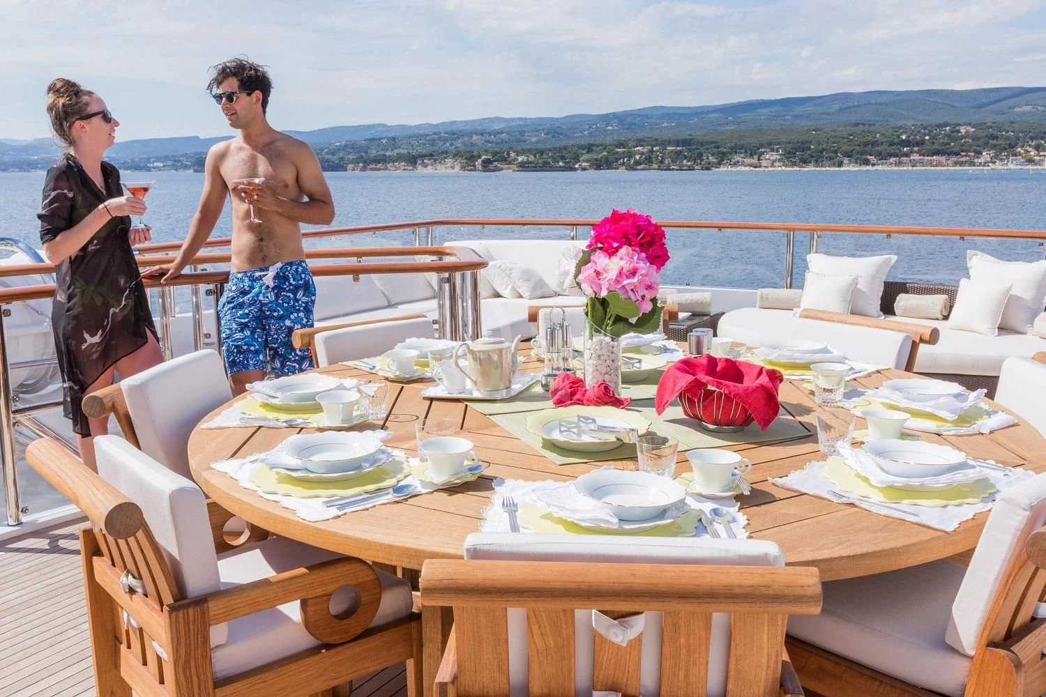 a man and woman standing on a table with food on it aboard FRIENDSHIP Yacht for Charter
