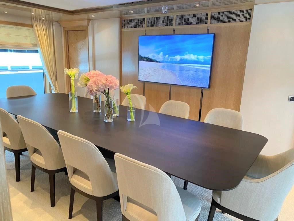 a table with chairs and a tv on the wall aboard FRIENDSHIP Yacht for Charter