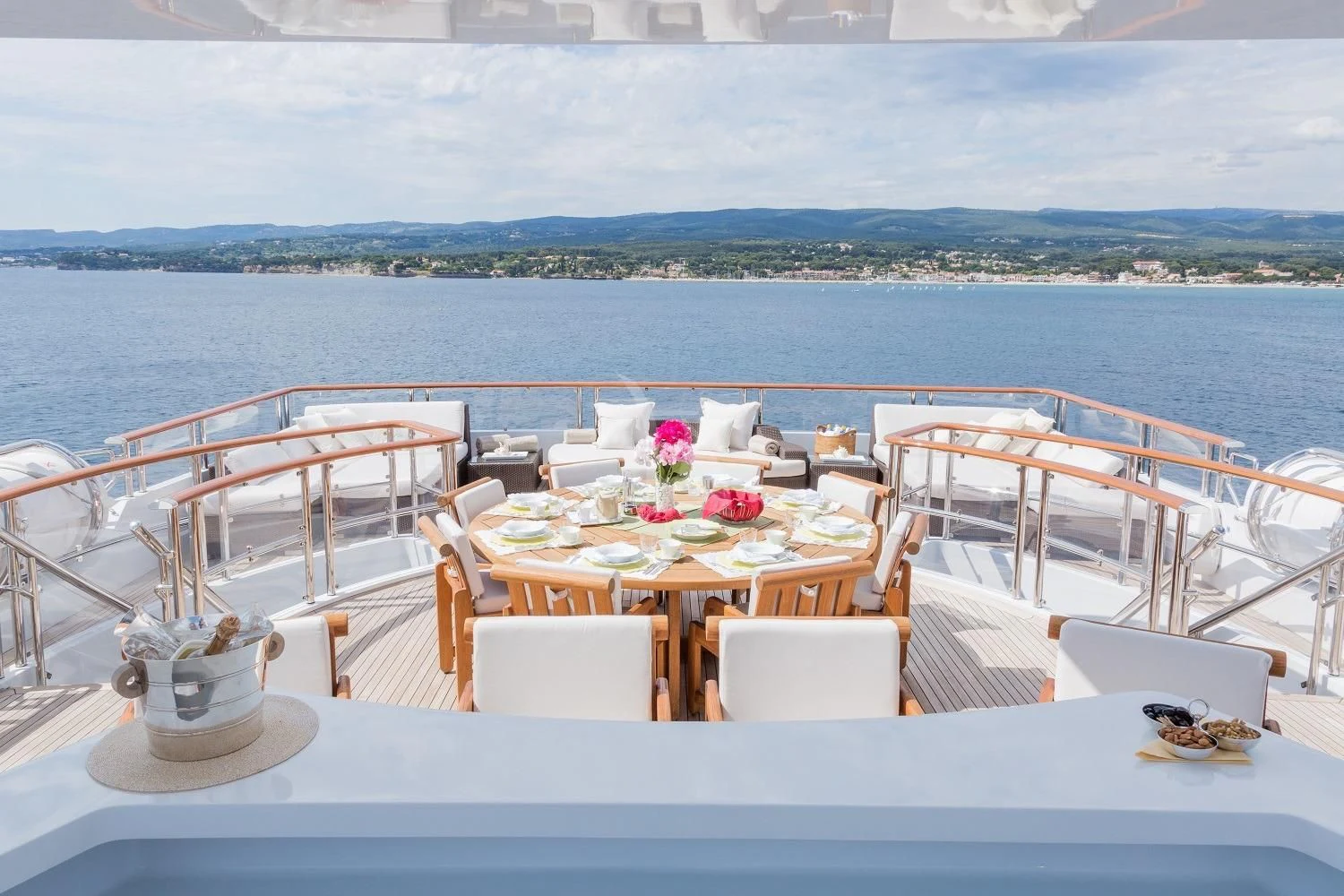 a table set for a meal on a balcony overlooking a large body of water aboard FRIENDSHIP Yacht for Charter