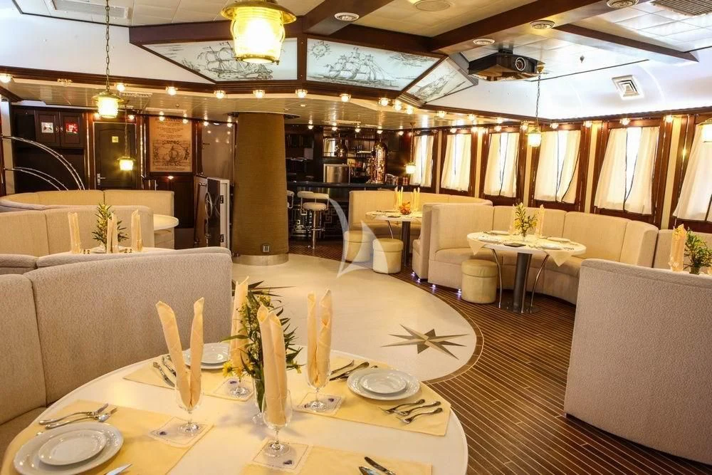 a room with tables and chairs aboard RUNNING ON WAVES Yacht for Charter