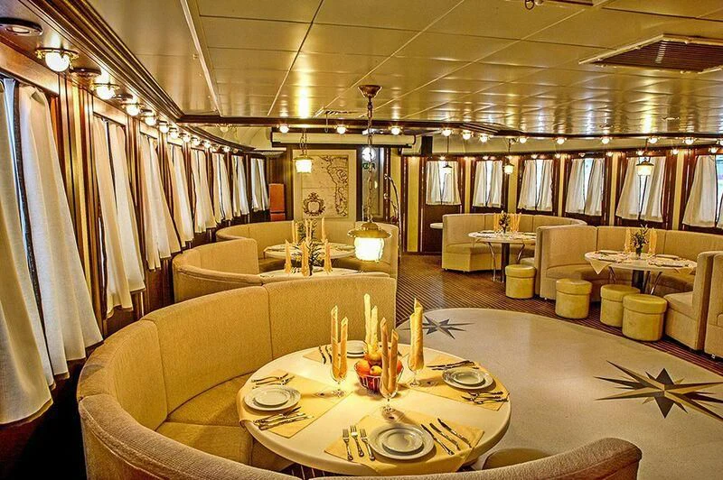 a large room with tables and chairs aboard RUNNING ON WAVES Yacht for Charter