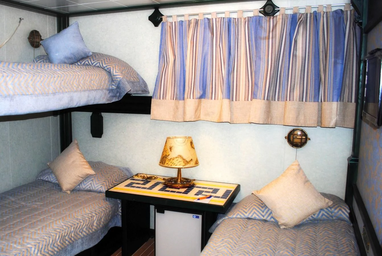 a bedroom with a bed and a lamp on a table aboard RUNNING ON WAVES Yacht for Charter
