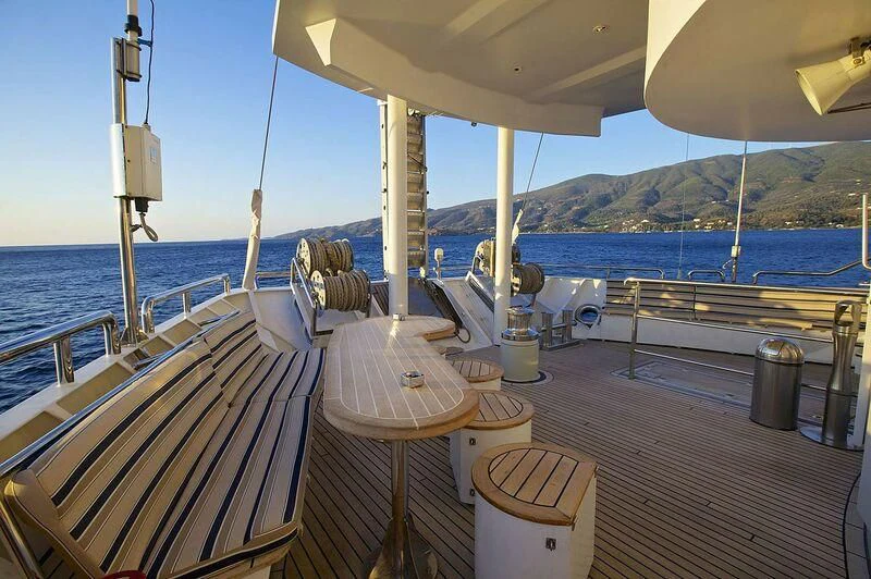 a deck with a table and chairs on it aboard RUNNING ON WAVES Yacht for Charter