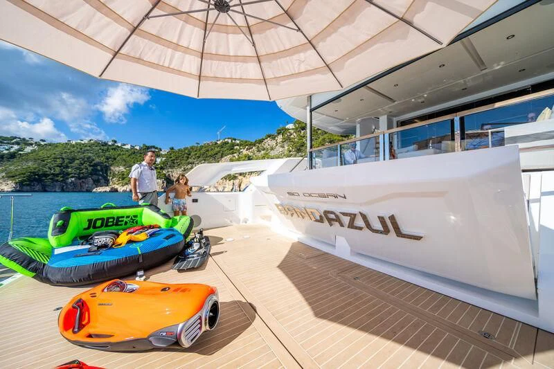 a person and a child standing next to a row of race cars aboard BANDAZUL Yacht for Sale
