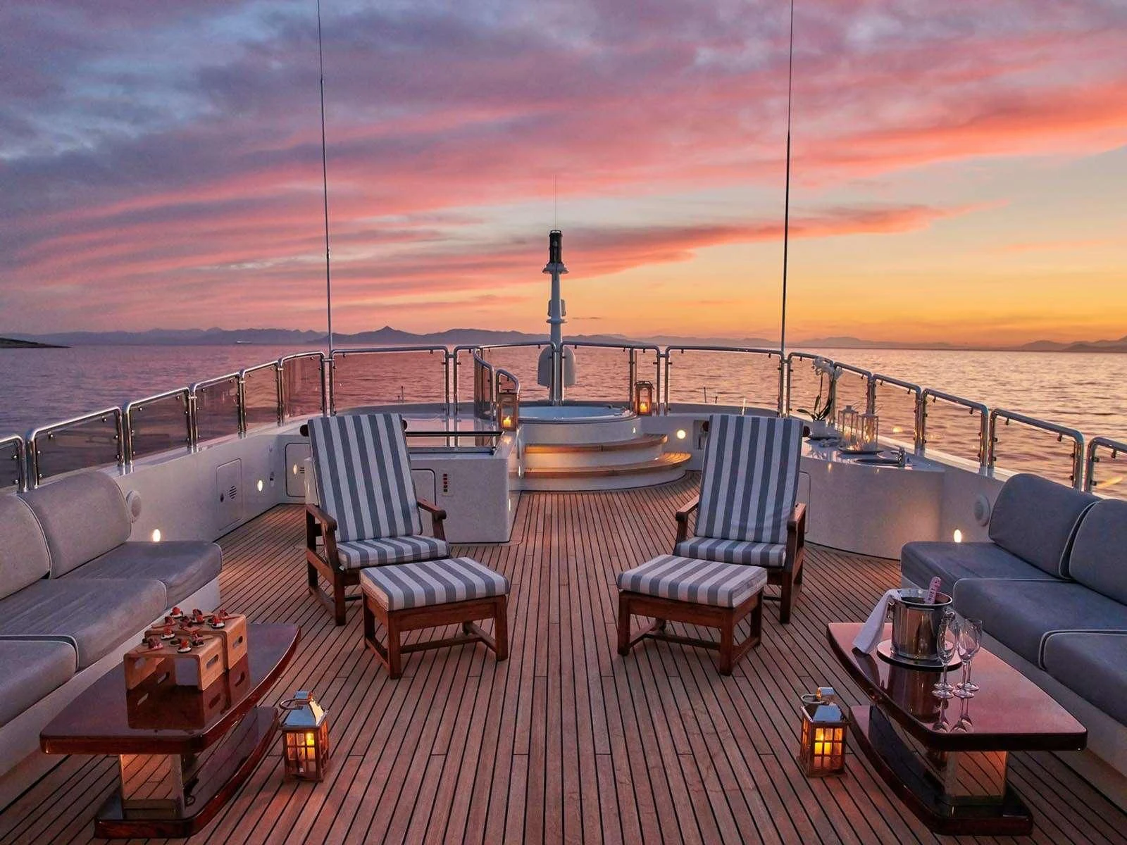 a deck with a view of the ocean and a sunset aboard ALEXANDRA Yacht for Charter