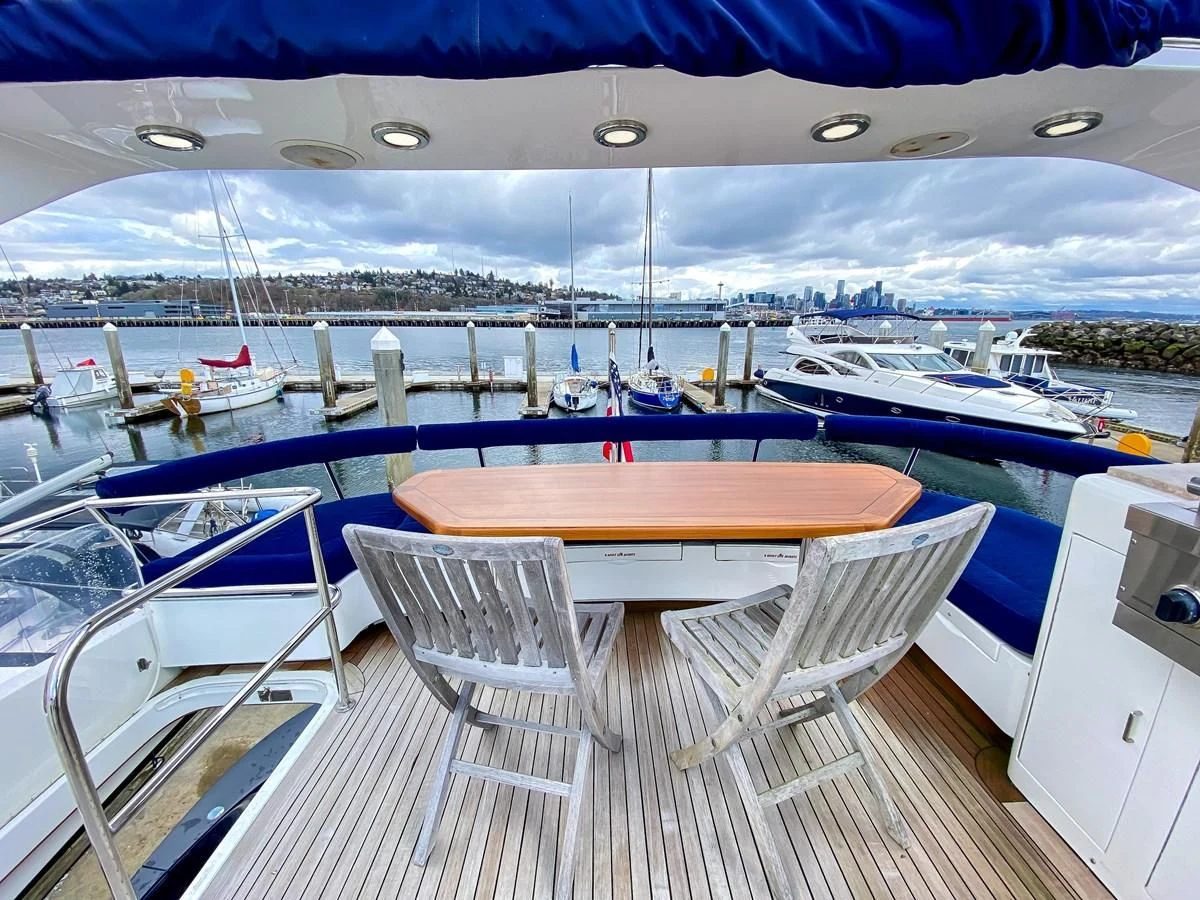 a deck with chairs and tables on it by a body of water aboard UNDAUNTED Yacht for Sale
