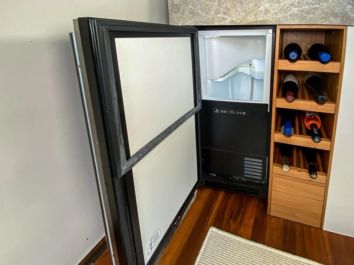 a black refrigerator next to a wooden cabinet aboard UNDAUNTED Yacht for Sale