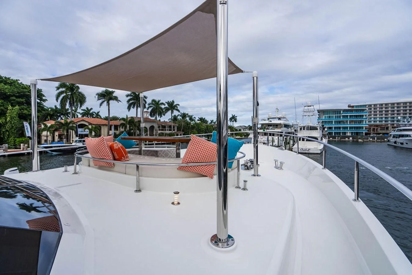 a deck with a white railing and a building with trees and a beach and water in the background aboard FAR NIENTE Yacht for Sale