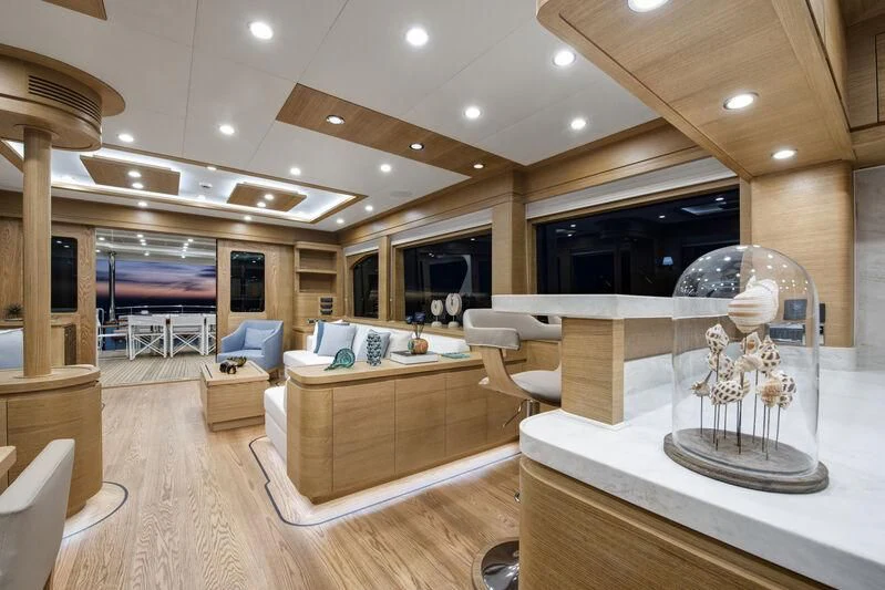 a large living room with a large glass table and a large chandelier aboard EMPIRE Yacht for Sale