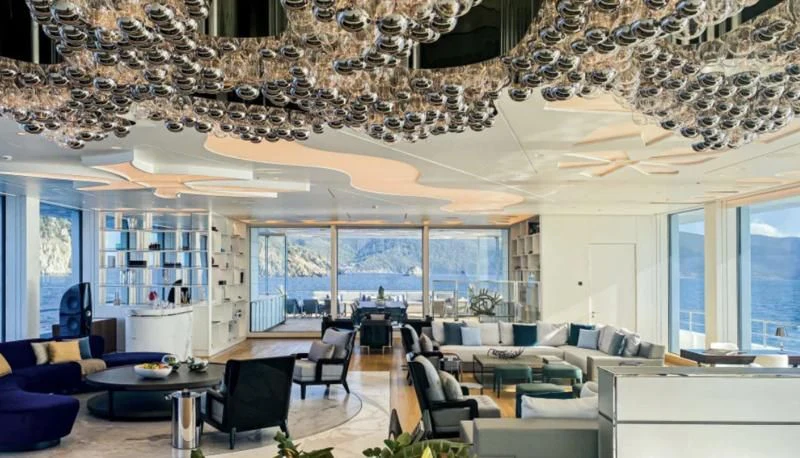 a large room with a chandelier and a table aboard LUMINOSITY Yacht for Sale