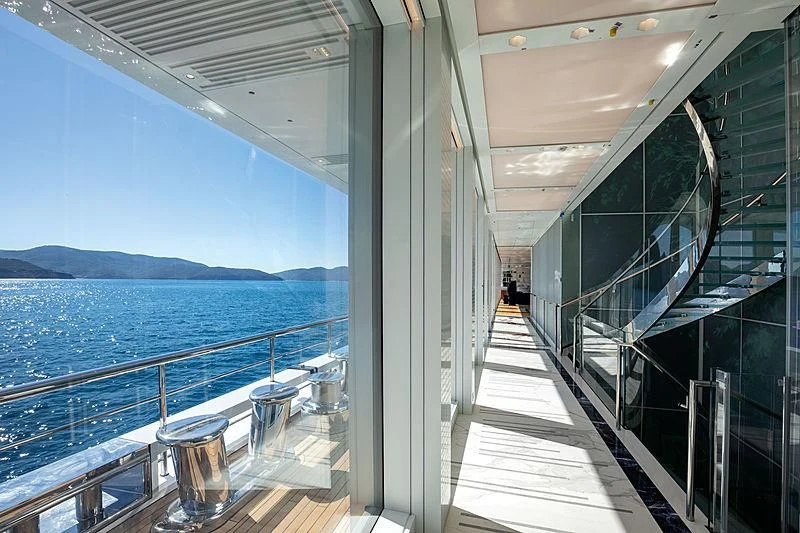 a long hallway with glass doors leading to a body of water aboard LUMINOSITY Yacht for Sale