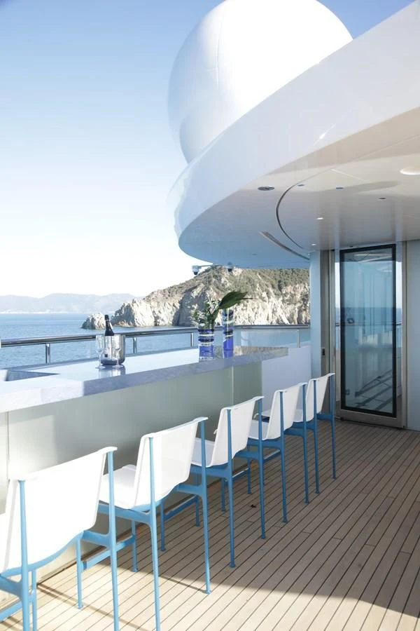 a white table and chairs on a deck with a view of the ocean aboard LUMINOSITY Yacht for Sale