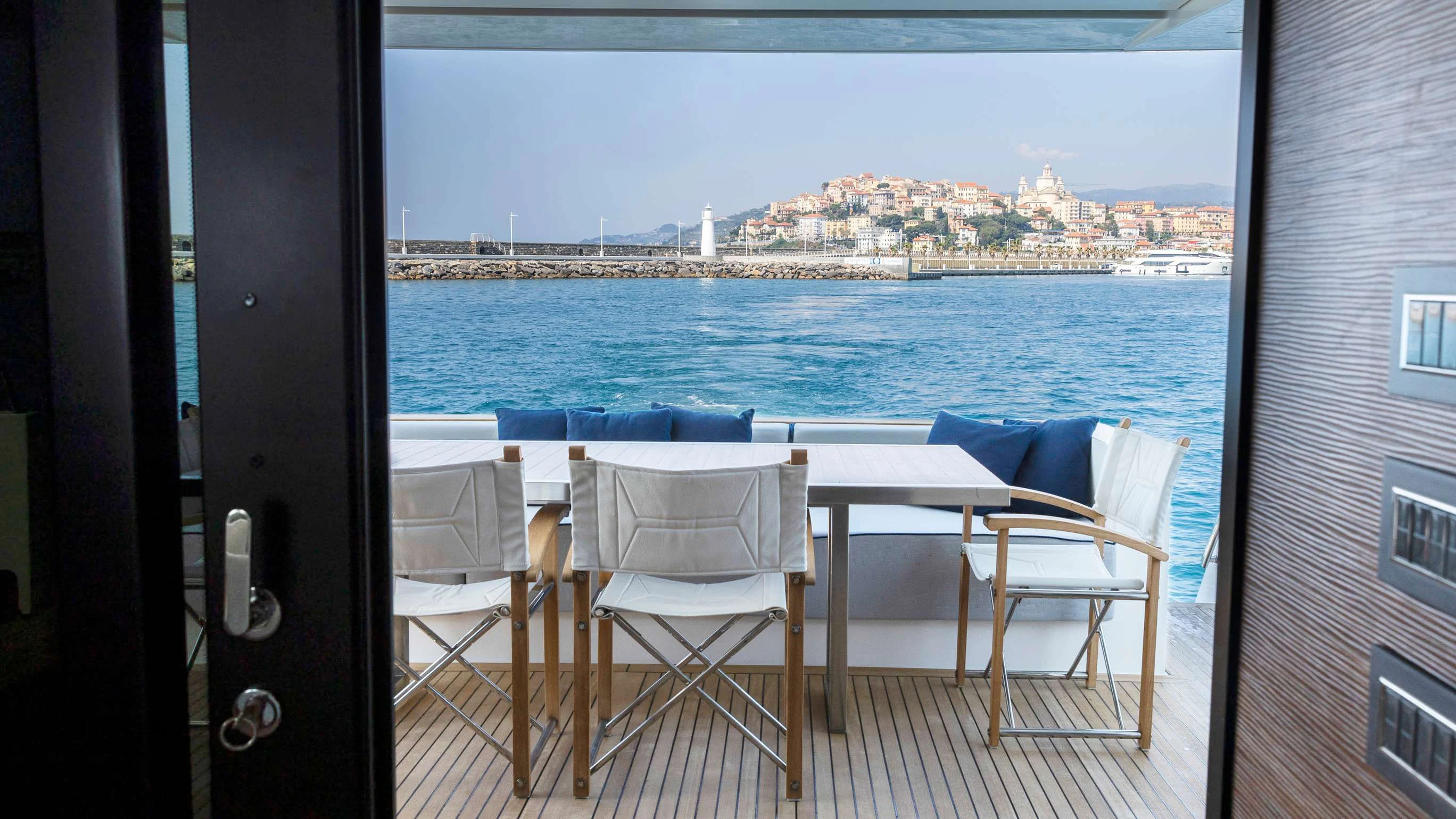 a table and chairs on a balcony overlooking a city aboard AMAN Yacht for Sale