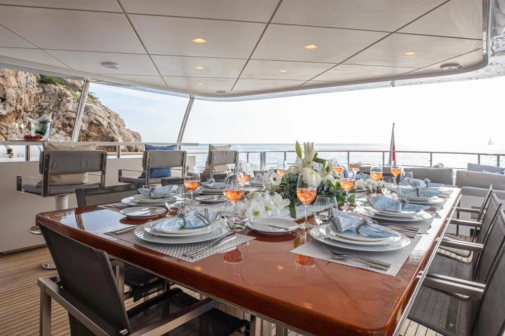 a large table with plates and glasses on it aboard ORSO 3 Yacht for Sale