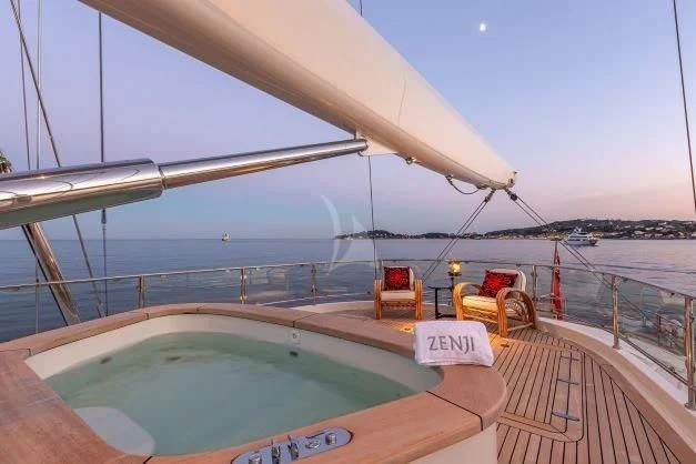 a large pool with a large deck overlooking a beach aboard ZENJI Yacht for Sale